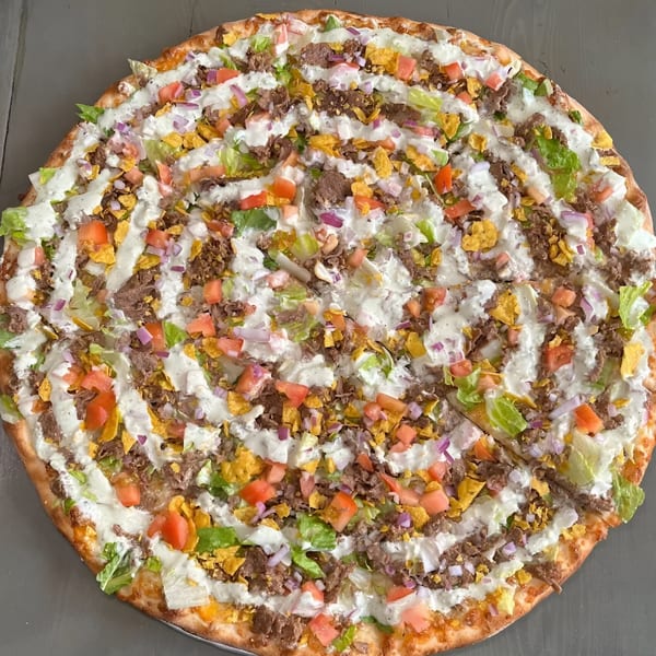 Krave It's taco pizza, topped with ground beef, lettuce, tomatoes, onions, tortilla chips, and sour cream.