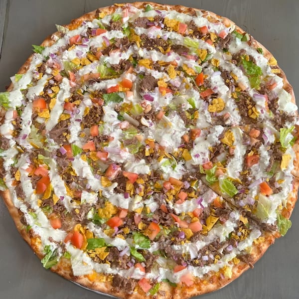 Krave It's taco pizza, topped with ground beef, lettuce, tomatoes, onions, and a creamy white sauce.