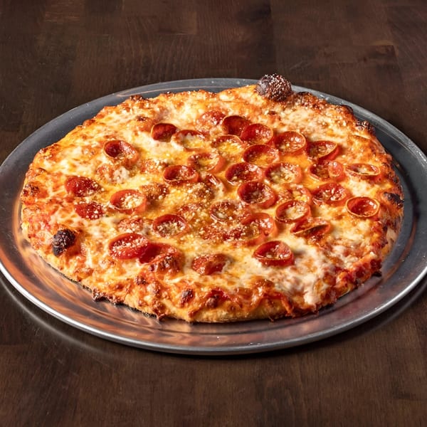A Krave It pepperoni pizza, golden brown with melted cheese and crispy crust, on a metal pan.
