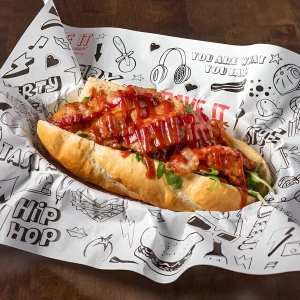 Krave It's chicken sandwich with red sauce and greens, served in branded paper.