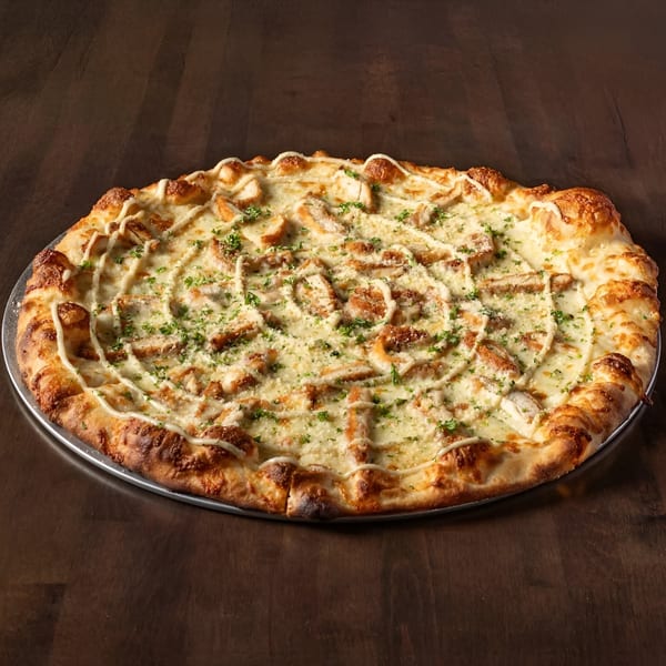 Krave It's chicken alfredo pizza, topped with white sauce, chicken, parsley, and a drizzle of white sauce.
