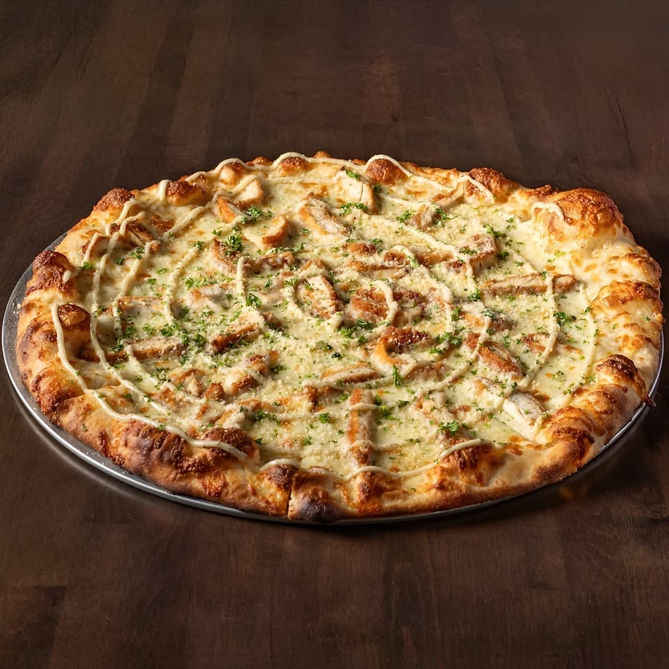 Krave It's chicken alfredo pizza, topped with white sauce, chicken, parsley, and a drizzle of white sauce.