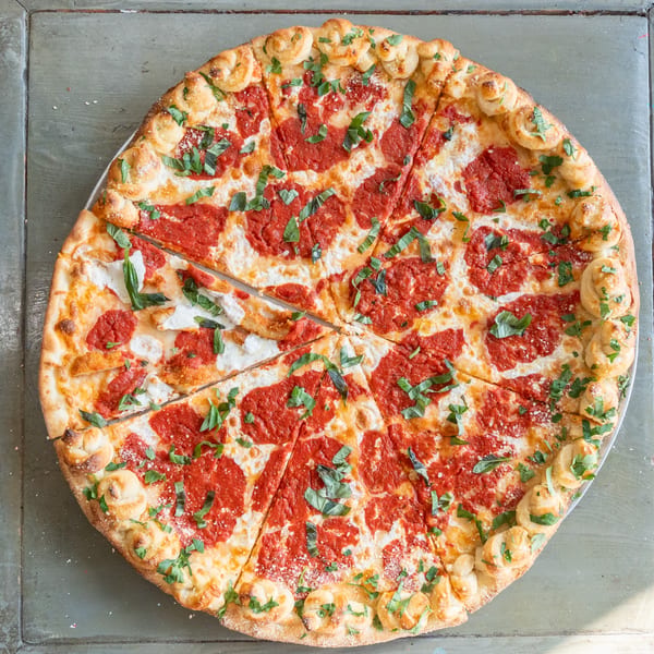 Krave It Pizza's sliced margherita pizza with garlic knot crust, tomato sauce, mozzarella, and fresh basil.