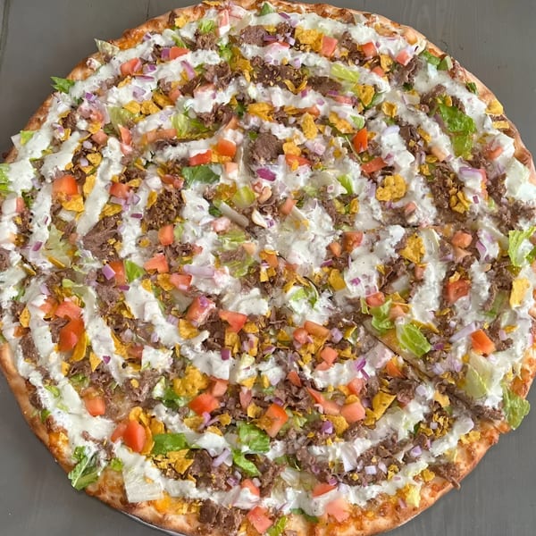 Krave It's taco pizza, topped with ground beef, lettuce, tomatoes, onions, tortilla chips, and white sauce.